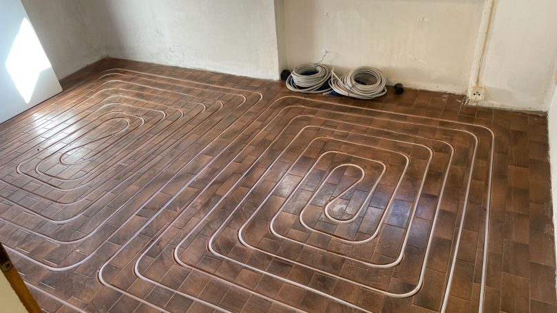 Warmes Fußbodensystem mit Kunststoffrohren in einem Wohnraum auf Fliesenboden.